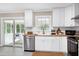 Open kitchen with white cabinets, butcher block countertop, stainless appliances, and access to the sunroom at 5121 Raintree Rd, Durham, NC 27712