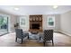 Open living room with a brick fireplace, wood floors, and natural light from large windows at 5121 Raintree Rd, Durham, NC 27712