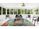 Light-filled sunroom featuring a floral rug and multiple windows overlooking the backyard at 5121 Raintree Rd, Durham, NC 27712