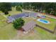 Aerial view of home with in-ground pool, barn, and storage shed set on a grassy lot with mature trees at 5200 Pulley Town Rd, Zebulon, NC 27597