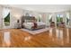 Large bedroom with hardwood floors, a bed, many windows with curtains, and bedside tables at 5200 Pulley Town Rd, Zebulon, NC 27597