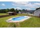 In-ground pool with diving board surrounded by green grass, trees, and home with covered porch and barn at 5200 Pulley Town Rd, Zebulon, NC 27597
