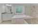 Bathroom featuring a soaking tub with a glass block window and granite countertops at 5805 Bayberry Ln, Raleigh, NC 27612