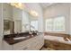 Bathroom with granite countertops, double sinks, large mirror, soaking tub, and tiled floor at 6217 Battleford Dr, Raleigh, NC 27612