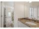 A bathroom with a granite countertop, single sink, and tiled shower, accessible from an adjacent bedroom at 6217 Battleford Dr, Raleigh, NC 27612