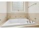 Large soaking tub with tile surround and glass block window for privacy at 6444 Kit Creek Rd, Morrisville, NC 27560