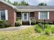 Welcoming brick home featuring a white railed porch and mature landscaping at 65 Opie Frazier Rd, Henderson, NC 27537