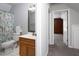 Full bath with oak vanity, decorative mirror, tub/shower combo, and floral curtain at 657 Lakeview Dr, Stem, NC 27581