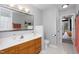 Well-lit bathroom featuring a wood vanity, decorative mirror, and doorway leading to a bedroom at 657 Lakeview Dr, Stem, NC 27581