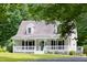 Exterior home view features a covered porch and inviting curb appeal surrounded by lush trees at 657 Lakeview Dr, Stem, NC 27581