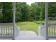Inviting porch view overlooking a vast green lawn, framed by white railings and natural beauty at 657 Lakeview Dr, Stem, NC 27581