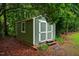 Well-maintained green storage shed with white trim and double doors, nestled in a serene, wooded backyard setting at 69 Margaret Pl, Chapel Hill, NC 27516