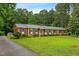 Traditional brick home with a long driveway and a lush green lawn surrounded by mature trees at 6909 Hickory Dr, Raleigh, NC 27603