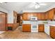 Cozy kitchen featuring wood cabinets, white appliances, and a view into an adjacent living area at 6909 Hickory Dr, Raleigh, NC 27603