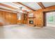 Inviting living room with wood paneling, a cozy brick fireplace, and built-in bookshelves at 6909 Hickory Dr, Raleigh, NC 27603
