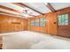 Spacious living room featuring wood paneled walls, carpet, and ample natural light from large windows at 6909 Hickory Dr, Raleigh, NC 27603