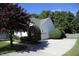 Long driveway leads to a home with a side-entry garage surrounded by mature trees and lush landscaping at 70 Glen Oaks Drive Dr, Youngsville, NC 27596