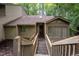 View of a quaint home exterior with a wooden walkway leading up to the front door and lush surrounding greenery at 73 Stoneridge Rd, Durham, NC 27705