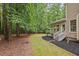 Side view of covered porch and stairs to back yard surrounded by mature trees at 7811 Still Crossing Rd, Chapel Hill, NC 27516