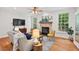 Cozy living room with a brick fireplace, hardwood floors, and bright windows at 7811 Still Crossing Rd, Chapel Hill, NC 27516