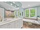 Main bathroom features a double sink vanity, soaking tub, tiled shower, and a large window overlooking the trees at 7811 Still Crossing Rd, Chapel Hill, NC 27516