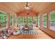 Bright sunroom with wood paneled walls, surrounding windows, and cozy seating at 7811 Still Crossing Rd, Chapel Hill, NC 27516