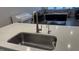 Kitchen island with a stainless steel sink, dishwasher, quartz countertops, and hardwood floors and a view to living room at 803 Courting St, Apex, NC 27523