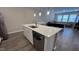 White kitchen island features a stainless steel sink, dishwasher, quartz countertops, and modern pendant lighting above at 803 Courting St, Apex, NC 27523