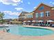 Resort-style swimming pool with lounge chairs, umbrellas, and brick community building in the background at 803 Courting St, Apex, NC 27523