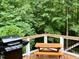 Outdoor deck featuring a grill and a picnic table, surrounded by lush greenery and trees at 8620 Brookdale Dr, Raleigh, NC 27613
