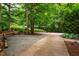 Long driveway surrounded by mature trees leading to a gravel parking area with basketball court at 8821 Oconee Ct, Chapel Hill, NC 27516