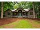 Charming home with wood siding, front porch, and a peaked roof surrounded by trees and landscaping at 8821 Oconee Ct, Chapel Hill, NC 27516