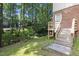 Brick home's backyard view featuring stairs, a wooden deck and lush trees at 905 Balmoral Dr, Cary, NC 27511