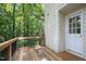 Wooden deck with black metal railing overlooking lush green trees and a white door entryway at 905 Balmoral Dr, Cary, NC 27511