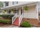 Inviting front porch with white railings, red stairs, and manicured landscaping at 905 Balmoral Dr, Cary, NC 27511