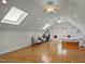 Bright bonus room featuring hardwood floors, skylights, ceiling fans, and built-in bookshelves at 100 Maywood Way, Chapel Hill, NC 27516