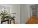 Hallway with hardwood floors and staircase, lit by a decorative chandelier at 100 Maywood Way, Chapel Hill, NC 27516