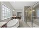 Bright bathroom featuring soaking tub, glass shower, tile floors, and a large window at 1029 Dozier Way, Cary, NC 27518