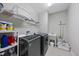 Well-equipped laundry room with modern washer and dryer, sink, storage shelves, and tiled flooring at 1029 Dozier Way, Cary, NC 27518