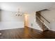 Living room with wood-look floors, chandelier, and stairs to the second floor at 107 Kimeo Way, Garner, NC 27529