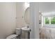 Clean half bathroom featuring a pedestal sink and toilet; part of a larger living space in the background at 110 Gallery Park Dr, Franklinton, NC 27525