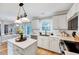 Bright kitchen featuring stainless steel appliances, white cabinets, stone countertops, and hardwood floors at 113 Fetzer Ct, Cary, NC 27513
