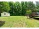 View of the backyard with a storage shed, treeline, and access stairs to the home's wooden deck at 117 Rack Ct, Willow Springs, NC 27592