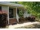 Inviting front porch with brick steps, white railings, and shade trees, perfect for relaxing and enjoying the outdoors at 117 Rack Ct, Willow Springs, NC 27592