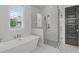 A modern bathroom showcases a luxurious bathtub and a glass-enclosed shower with white tile at 120 Hazel Alder Ct, Holly Springs, NC 27540