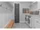 Organized laundry room with washer, dryer, storage, and bench at 120 Hazel Alder Ct, Holly Springs, NC 27540