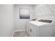 Modern laundry room with white appliances, a wire rack for storage, and a framed piece of art at 1213 Everton Ave, Durham, NC 27703