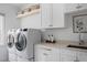 Functional laundry room with white cabinetry, counter space, and modern washer/dryer at 123 Trellingwood Dr, Morrisville, NC 27560