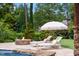 Relaxing poolside lounge area with comfortable chairs, a sun umbrella, and a fire pit, perfect for enjoying the outdoors at 123 Trellingwood Dr, Morrisville, NC 27560