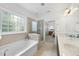 Bright bathroom showcasing a soaking tub and a double sink vanity with a doorway to the bedroom at 1720 Laurel Park Pl, Cary, NC 27511